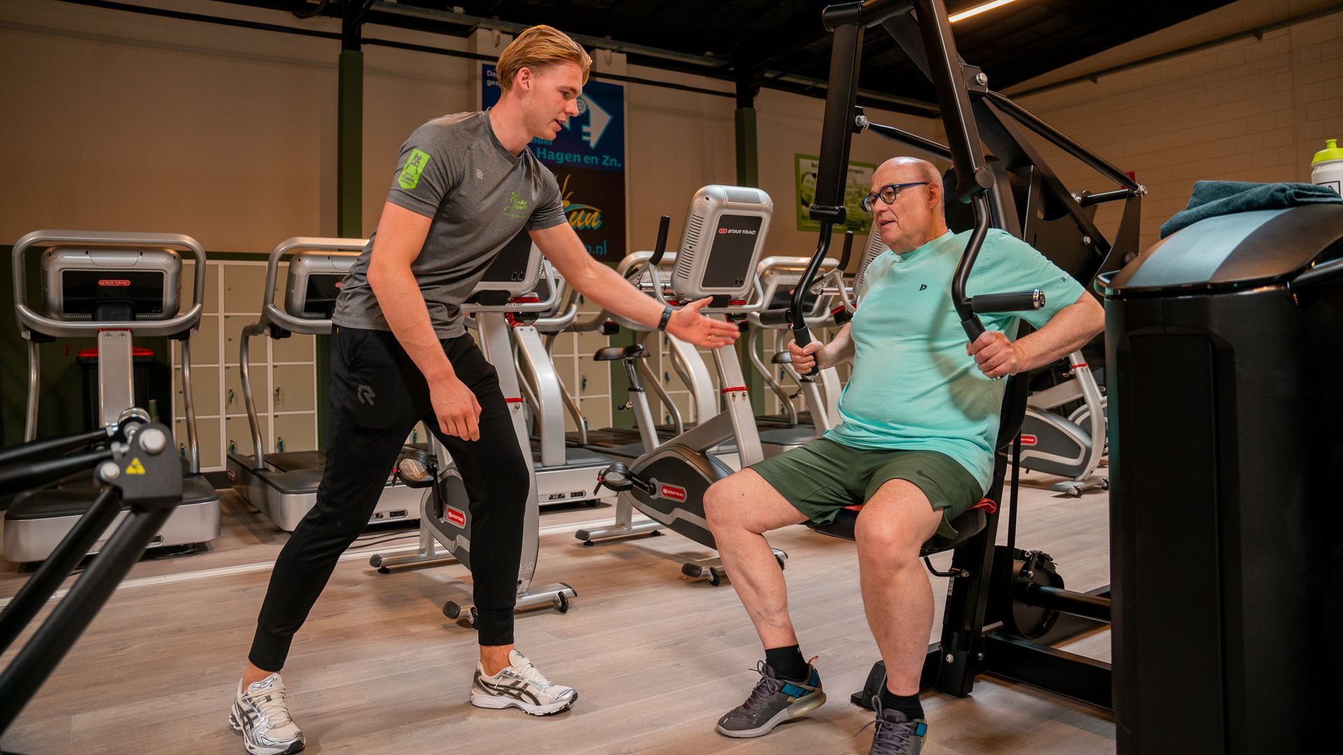 Een man helpt een andere man met trainen in de sportschool.