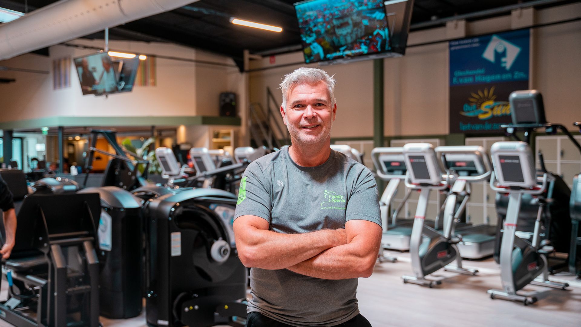 Een man staat in een sportschool met zijn armen over elkaar.