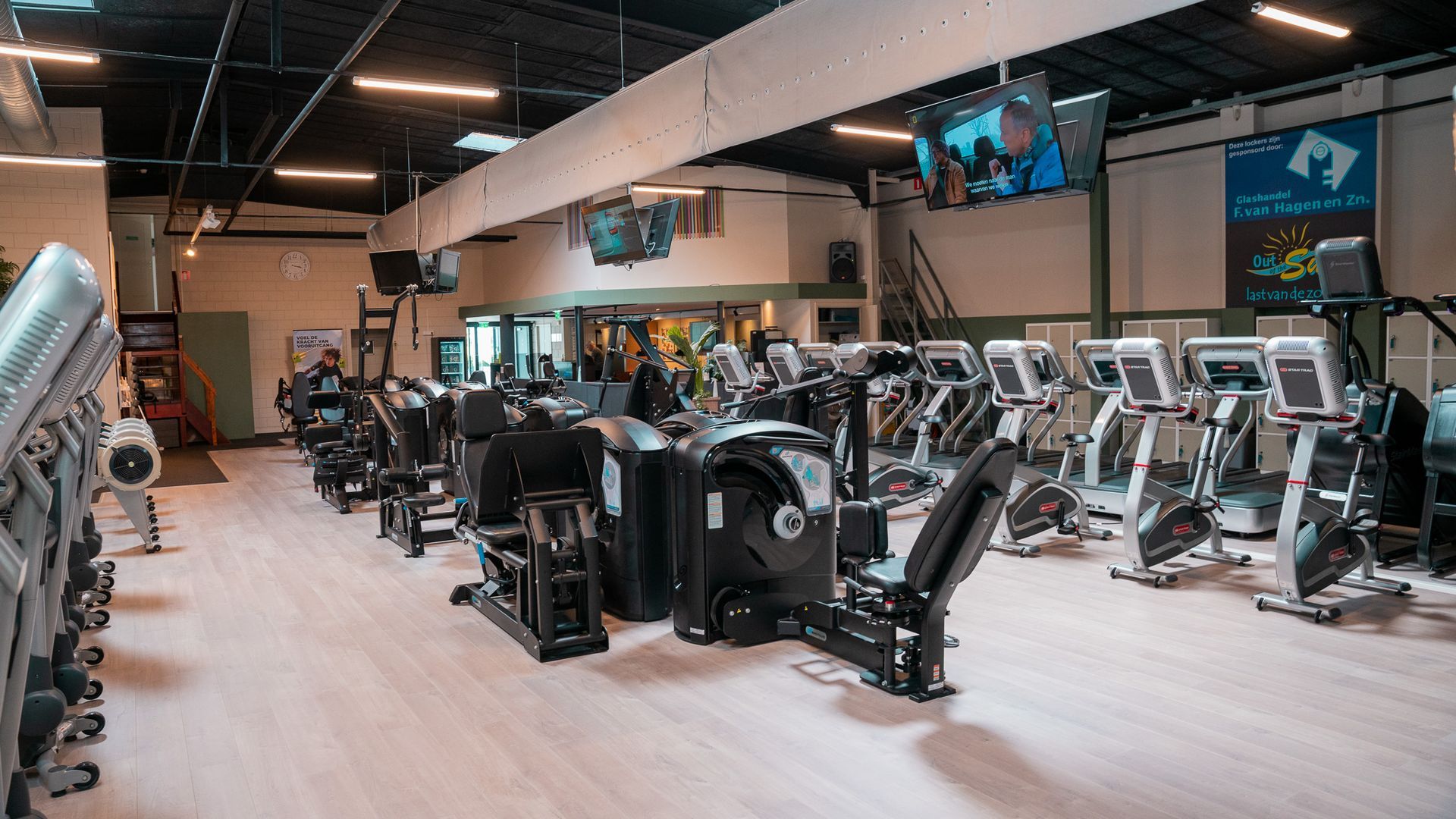 Een grote sportschool vol met fitnessapparatuur.