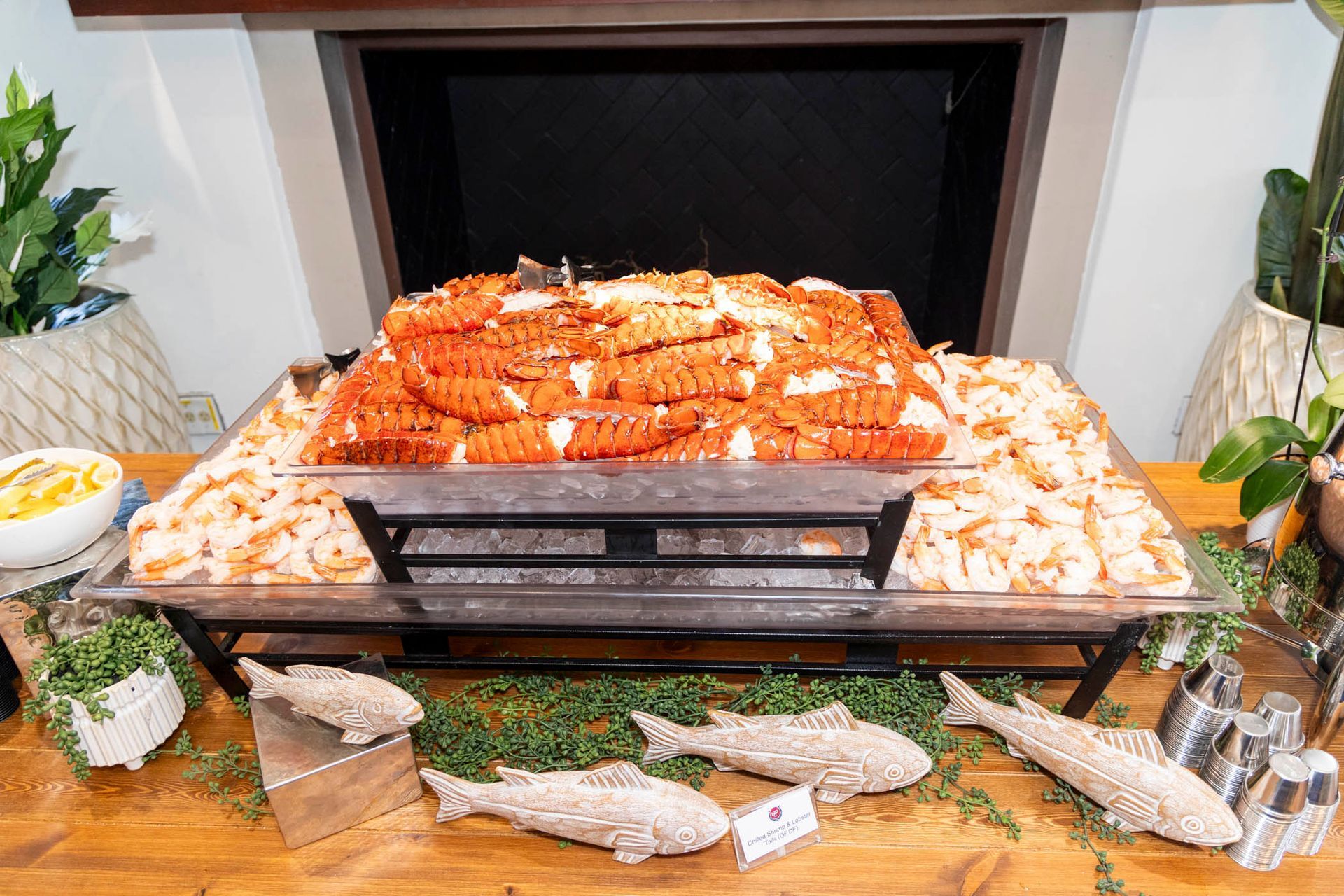 A large tray of shrimp is sitting on a wooden table in front of a fireplace.