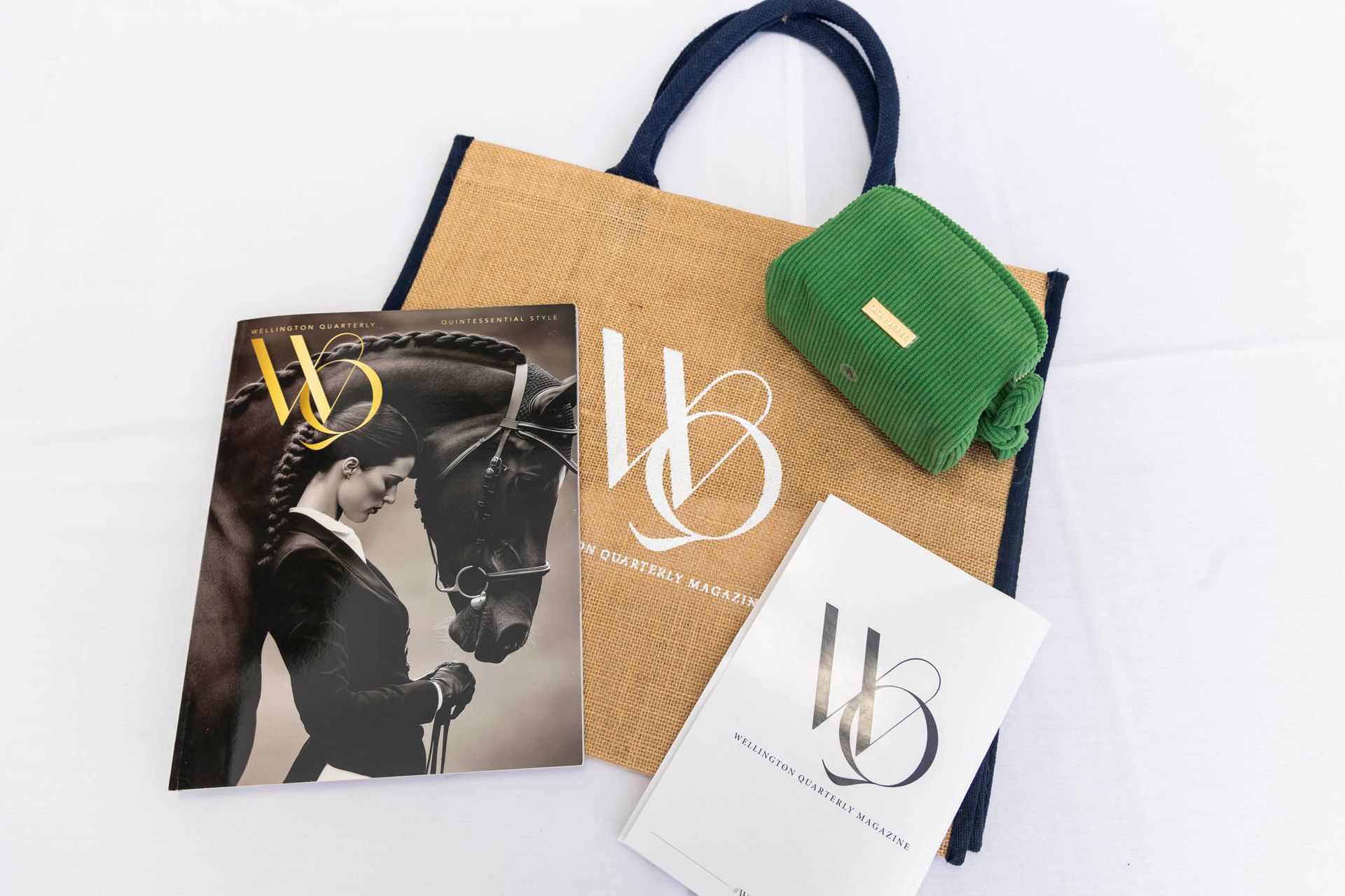 A bag , a magazine , and a green purse are on a table.