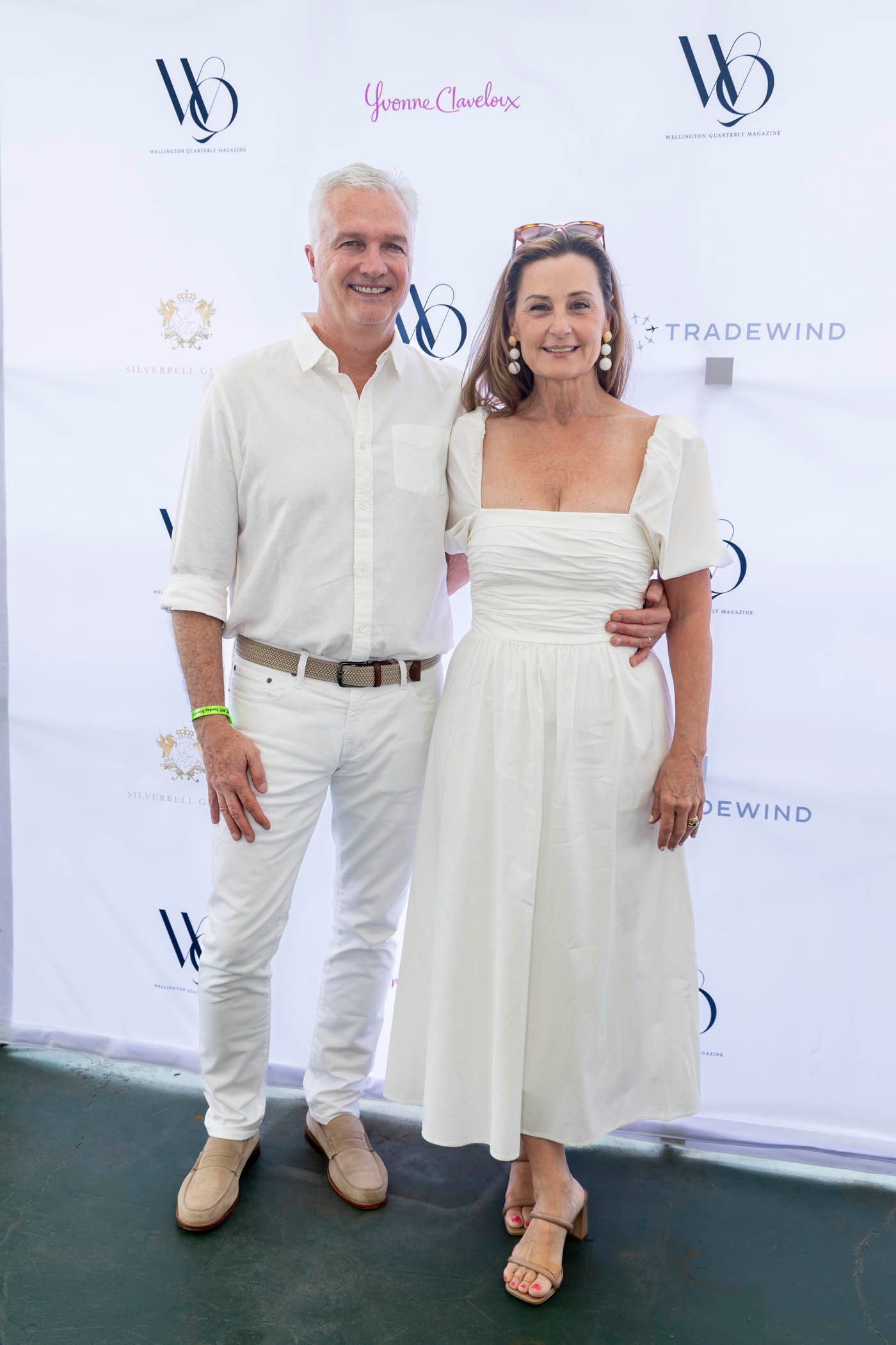 A man and a woman are standing next to each other in front of a white wall.