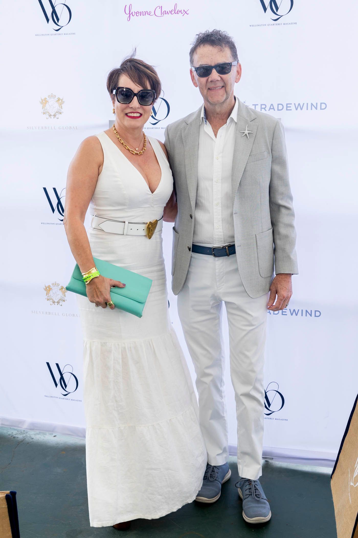 A man and a woman are posing for a picture in front of a white wall.