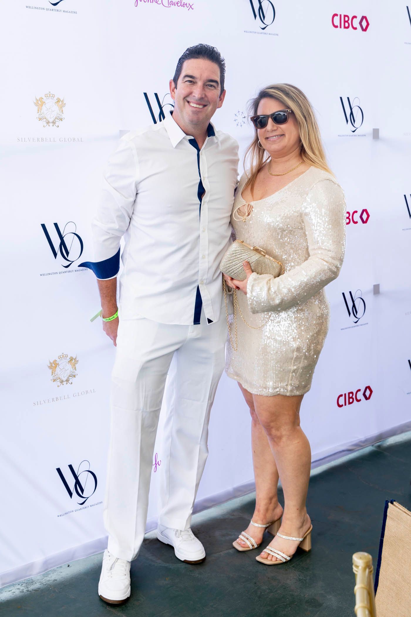 A man and a woman are standing next to each other in front of a white wall.