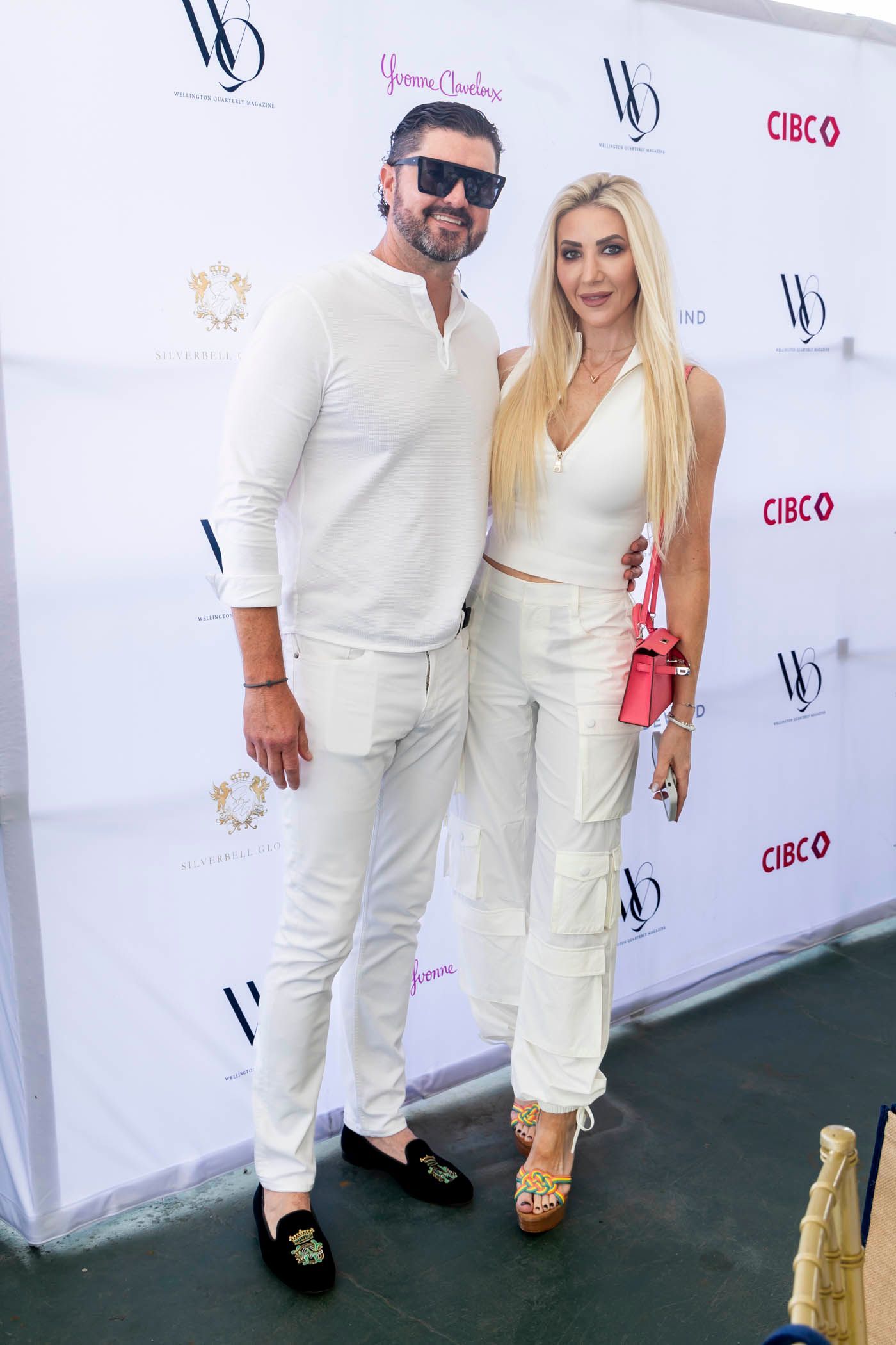 A man and a woman are standing next to each other in front of a white wall.