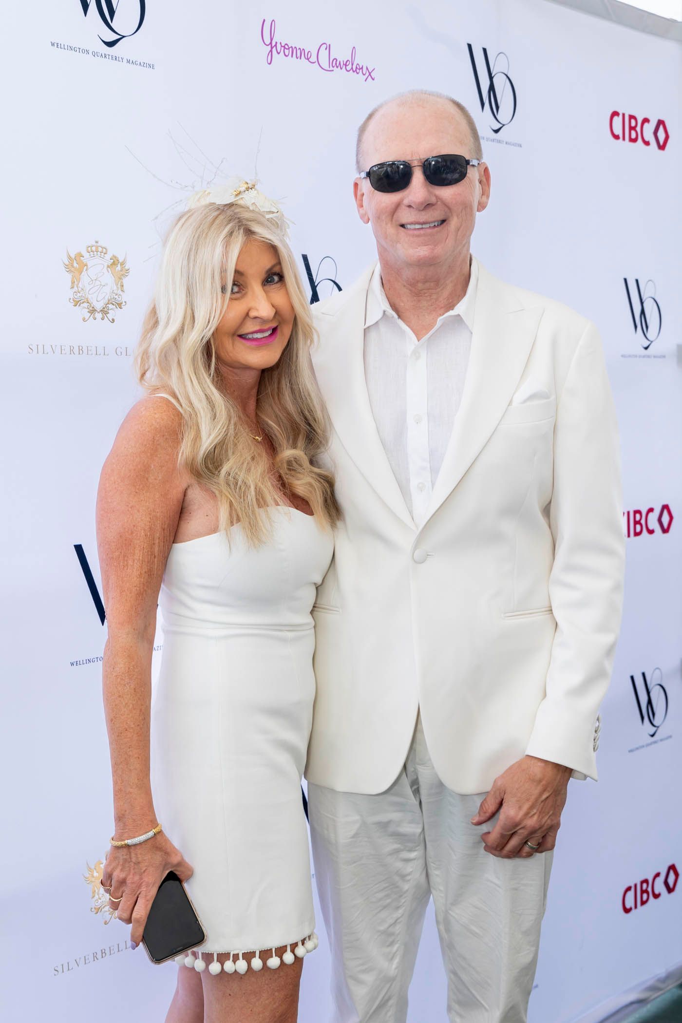 A man and a woman are posing for a picture in front of a white wall.