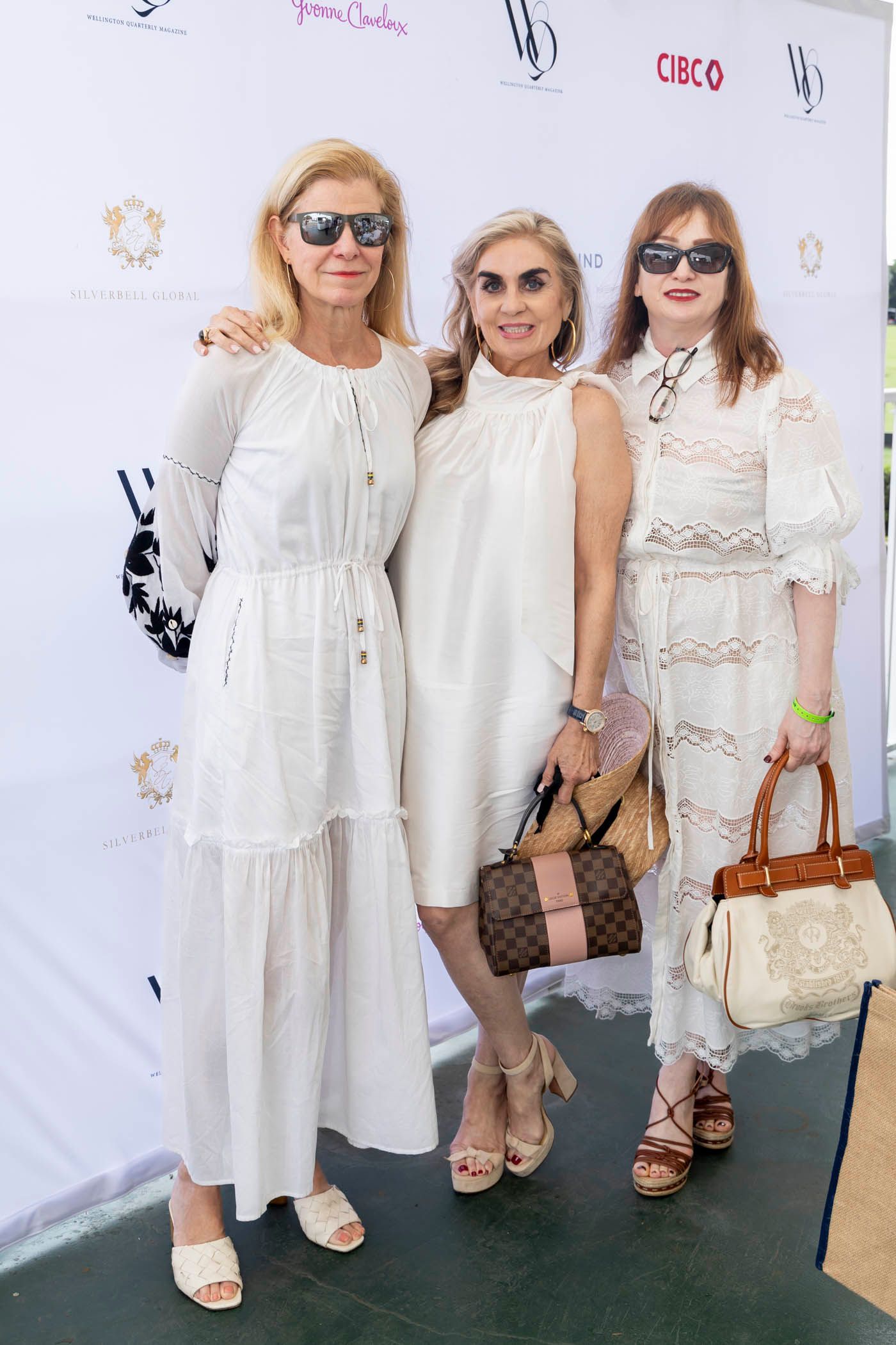 Three women in white dresses are posing for a picture.