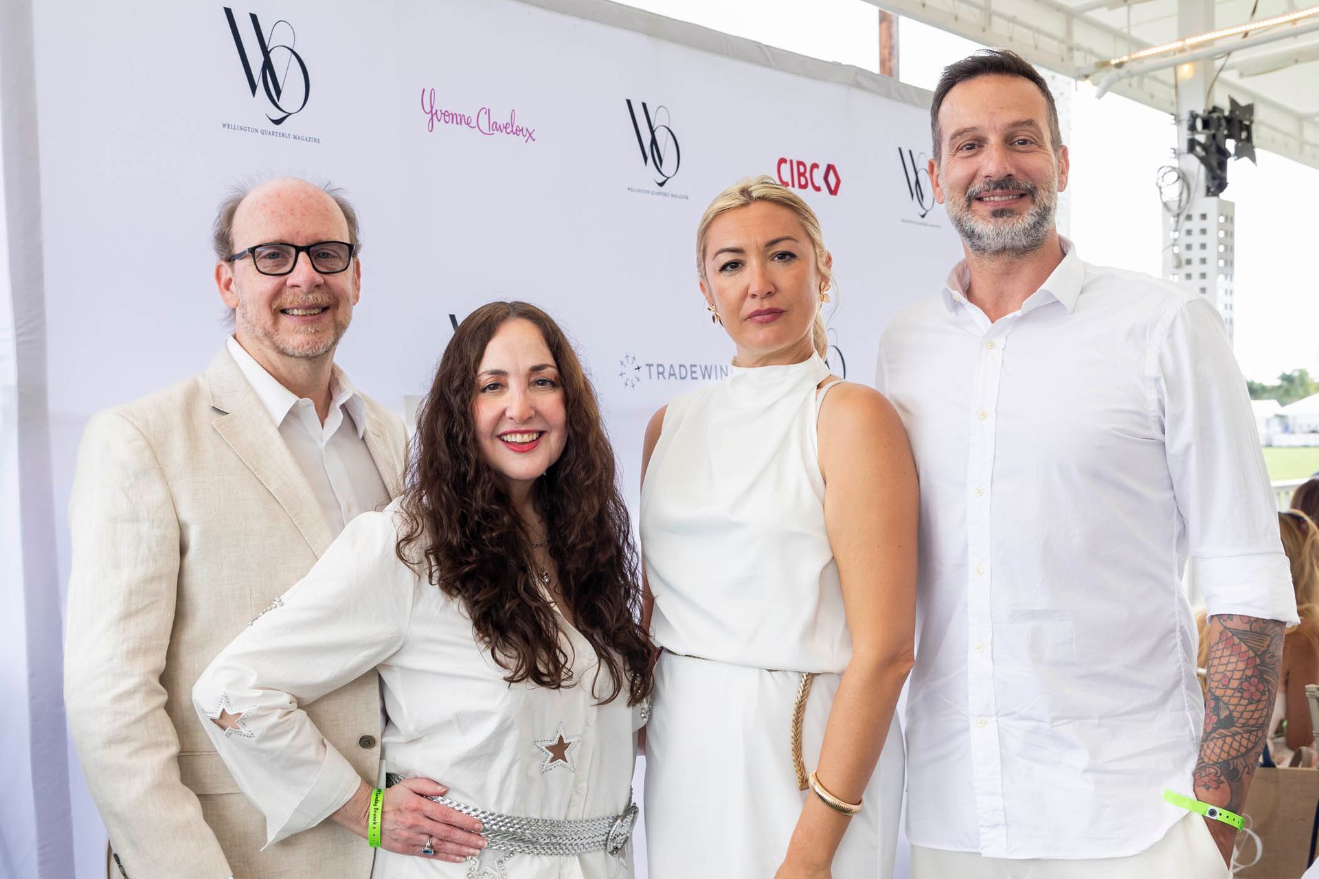A group of people standing next to each other in front of a white wall.