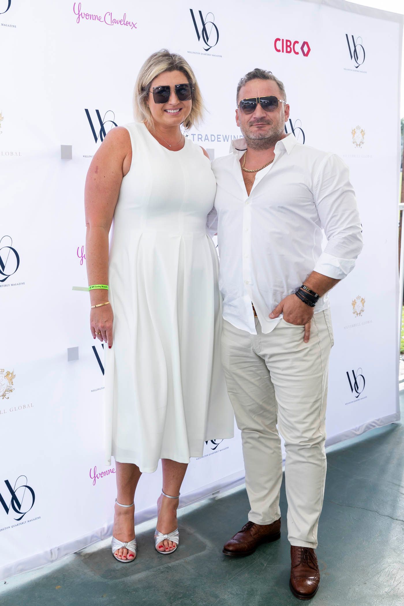 A man and a woman are posing for a picture in front of a white wall.