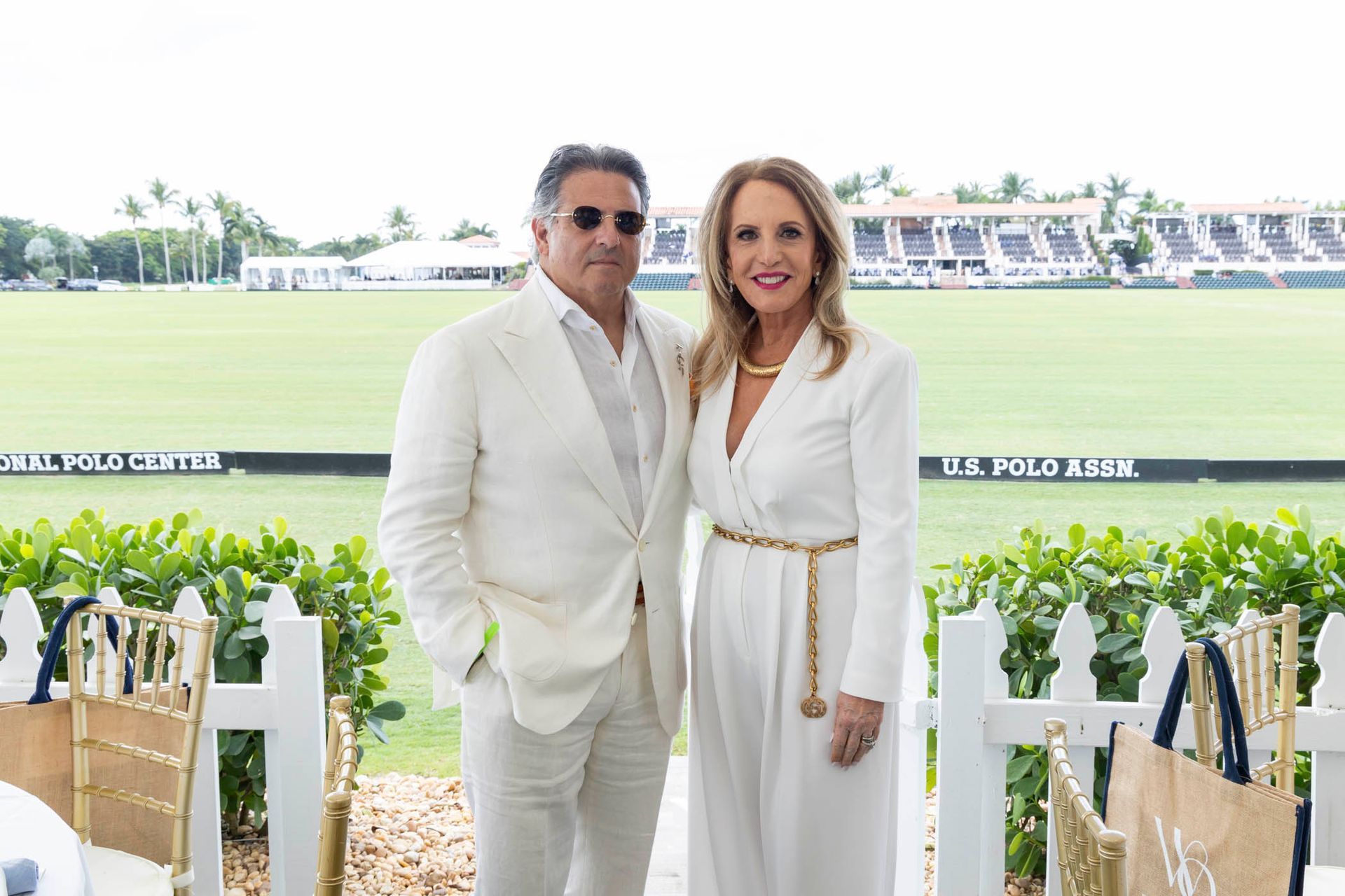 A man and a woman are posing for a picture in front of a polo field.