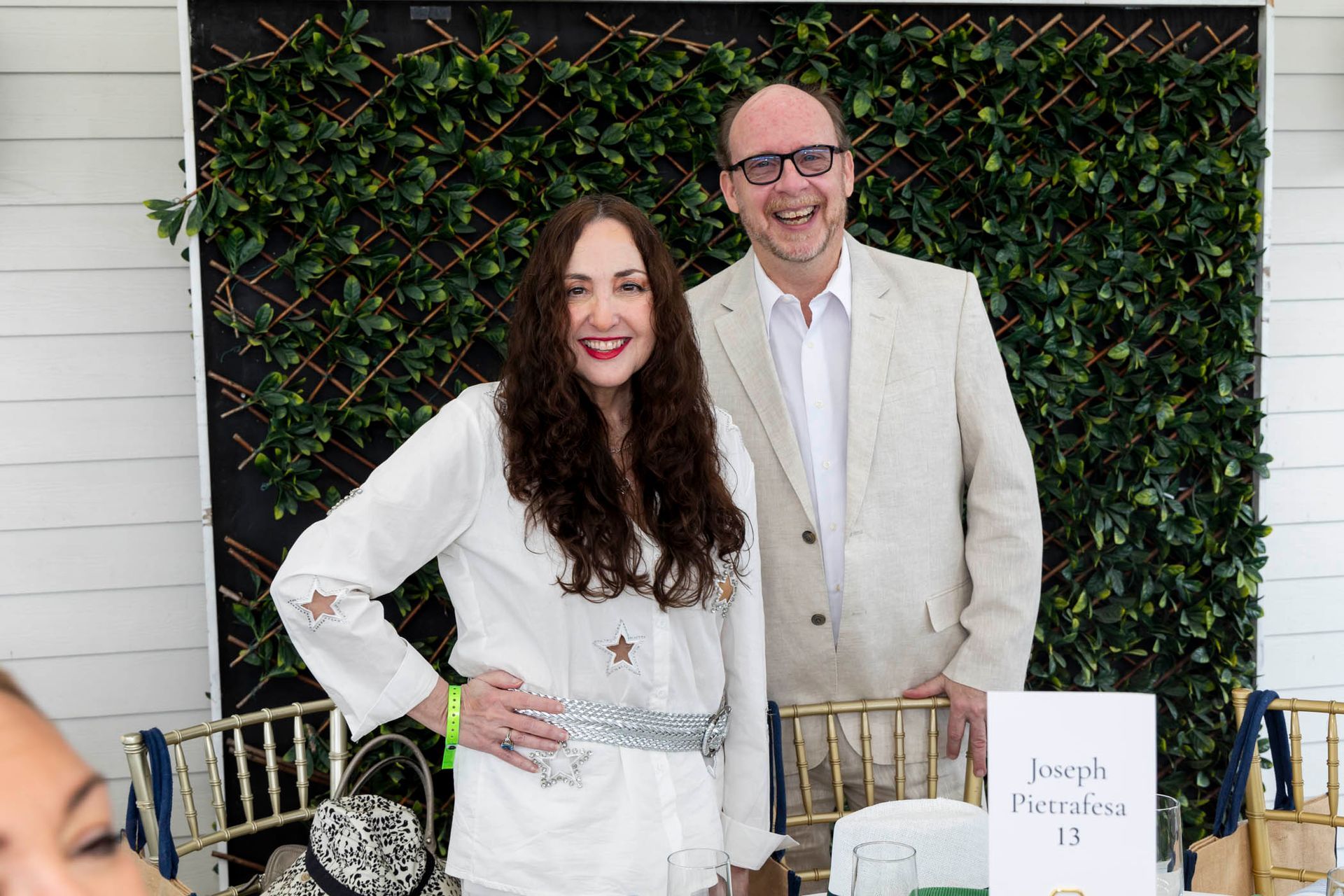 A man and a woman are posing for a picture in front of a green wall.