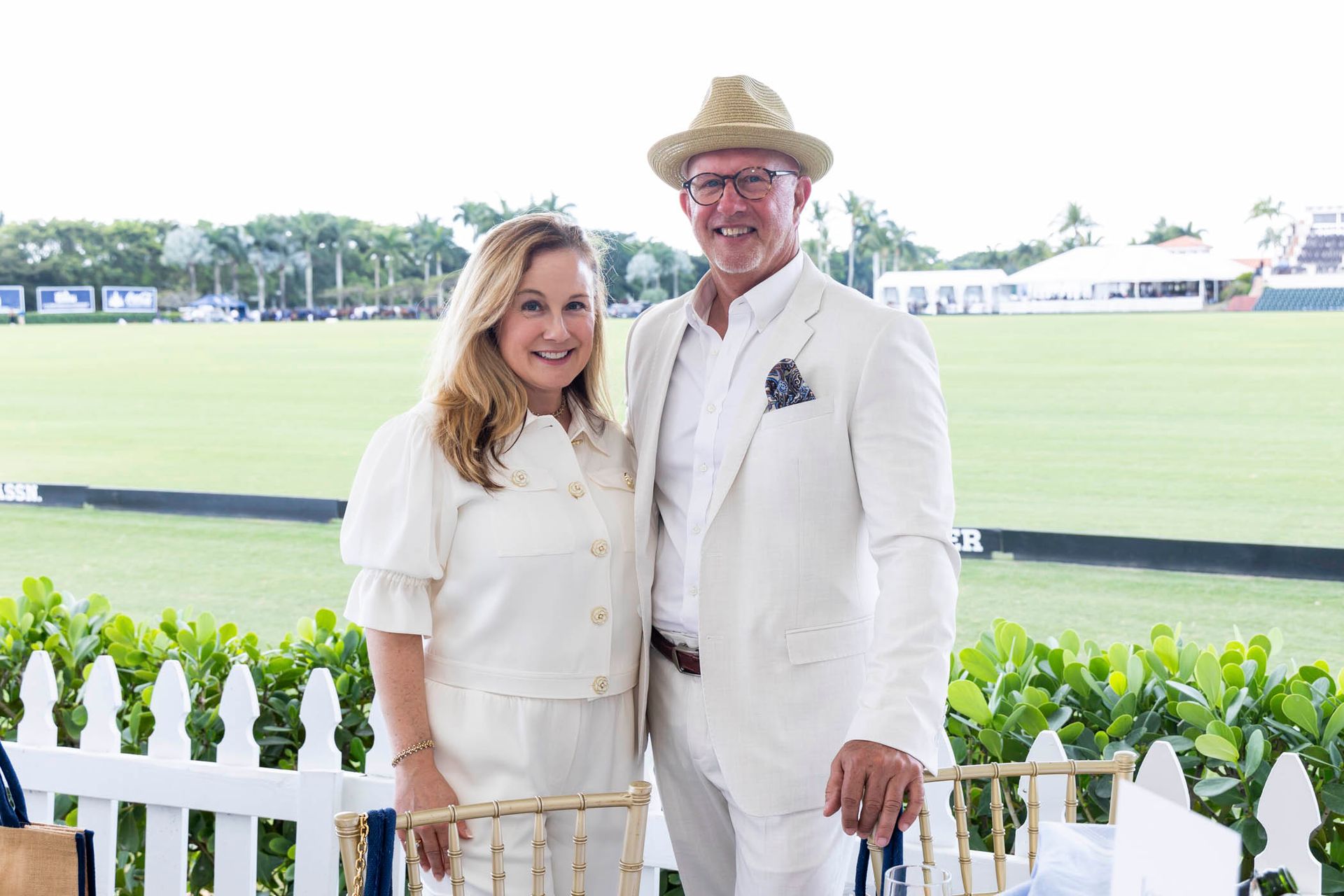 A man and a woman are posing for a picture in front of a polo field.