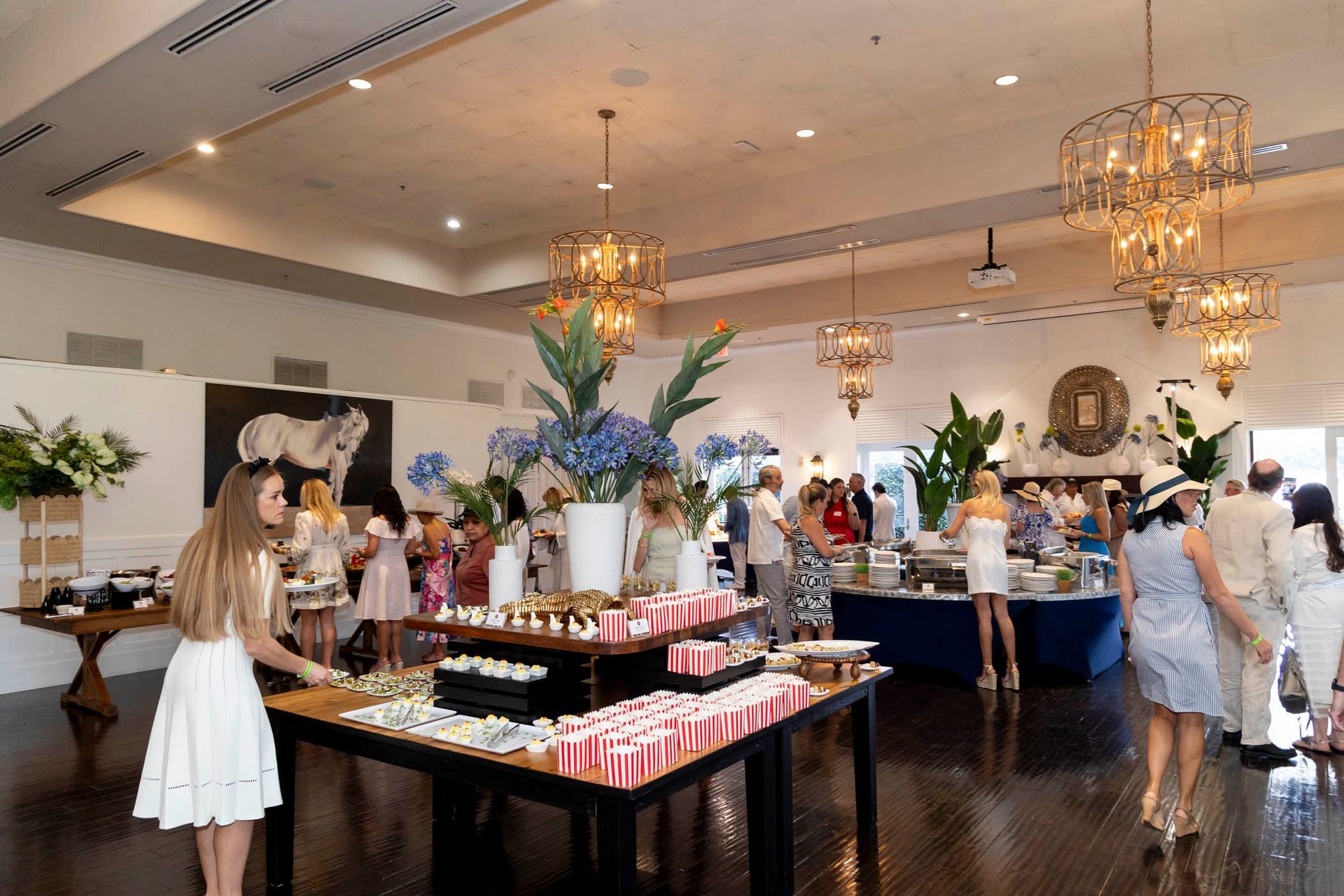 A woman in a white dress is standing in front of a buffet table in a large room.