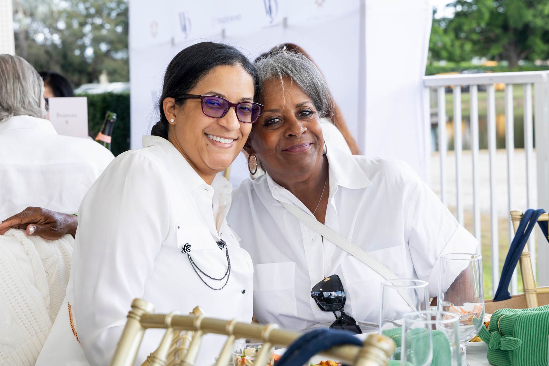 Two women are posing for a picture while sitting at a table.
