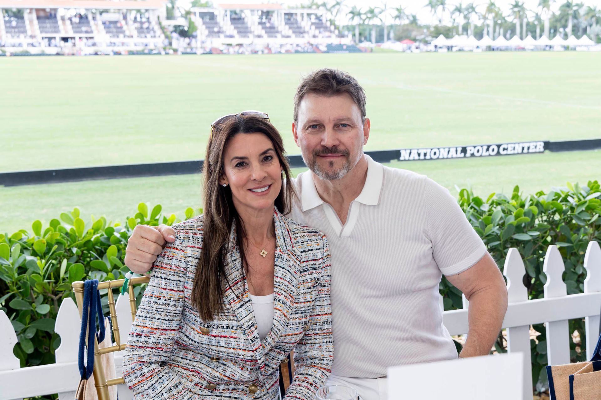 A man and a woman are posing for a picture in front of a polo field.