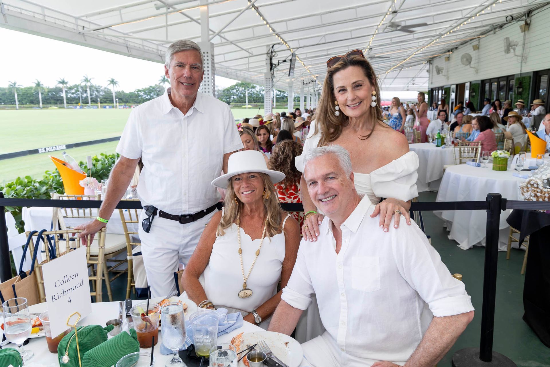 A group of people are posing for a picture while sitting at a table.
