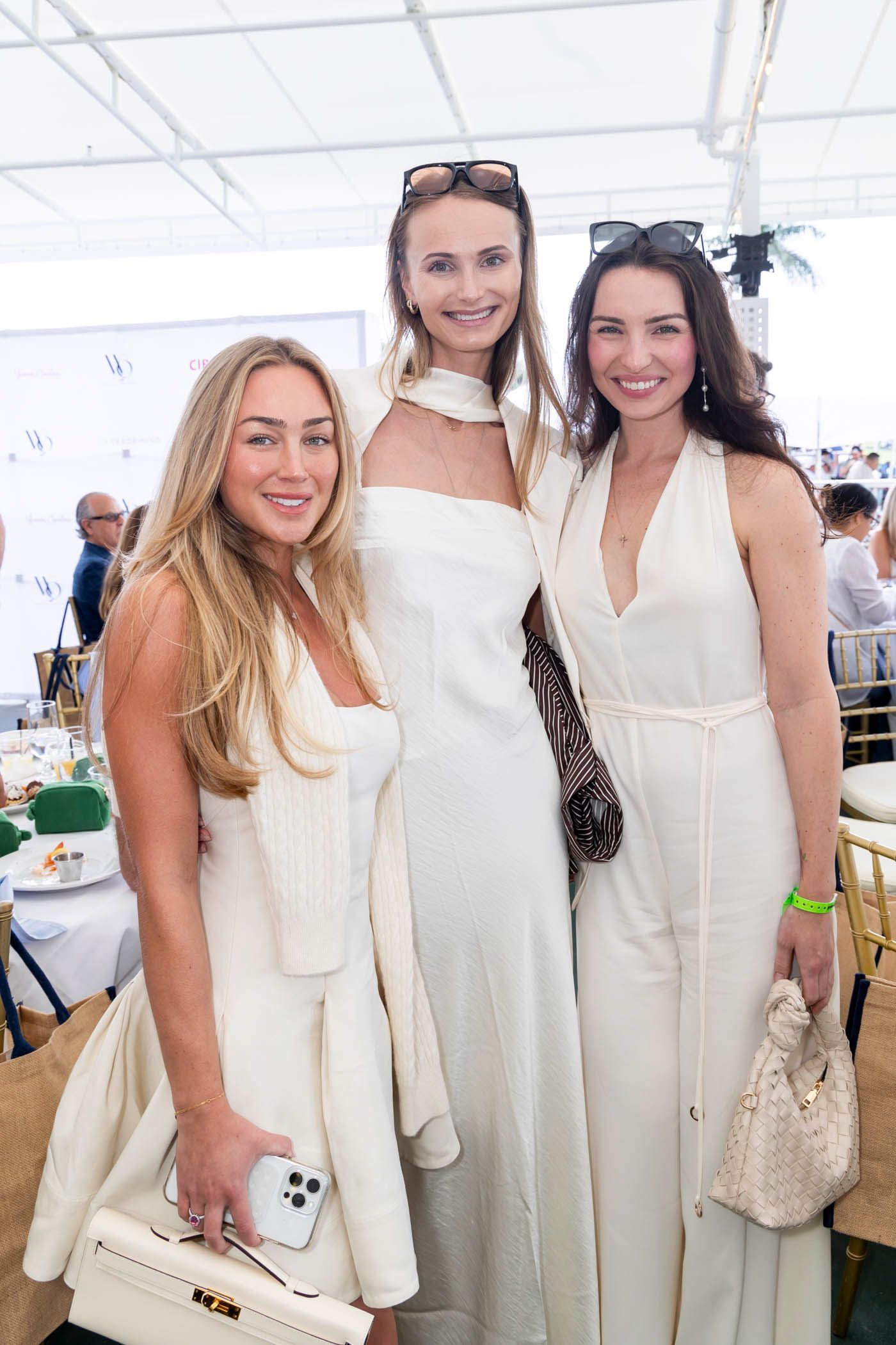 Three women in white dresses are posing for a picture.