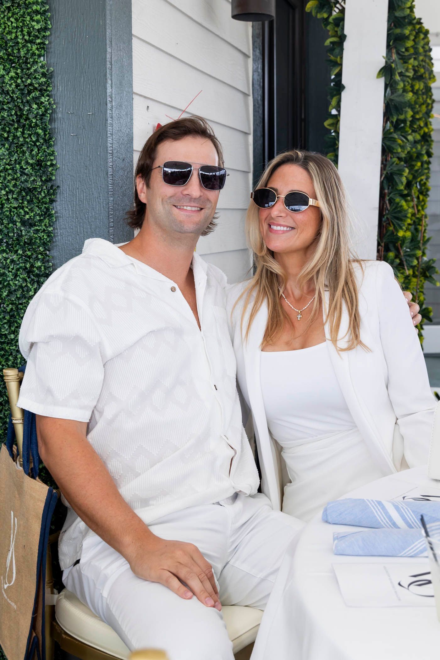 A man and a woman wearing all white are sitting at a table.