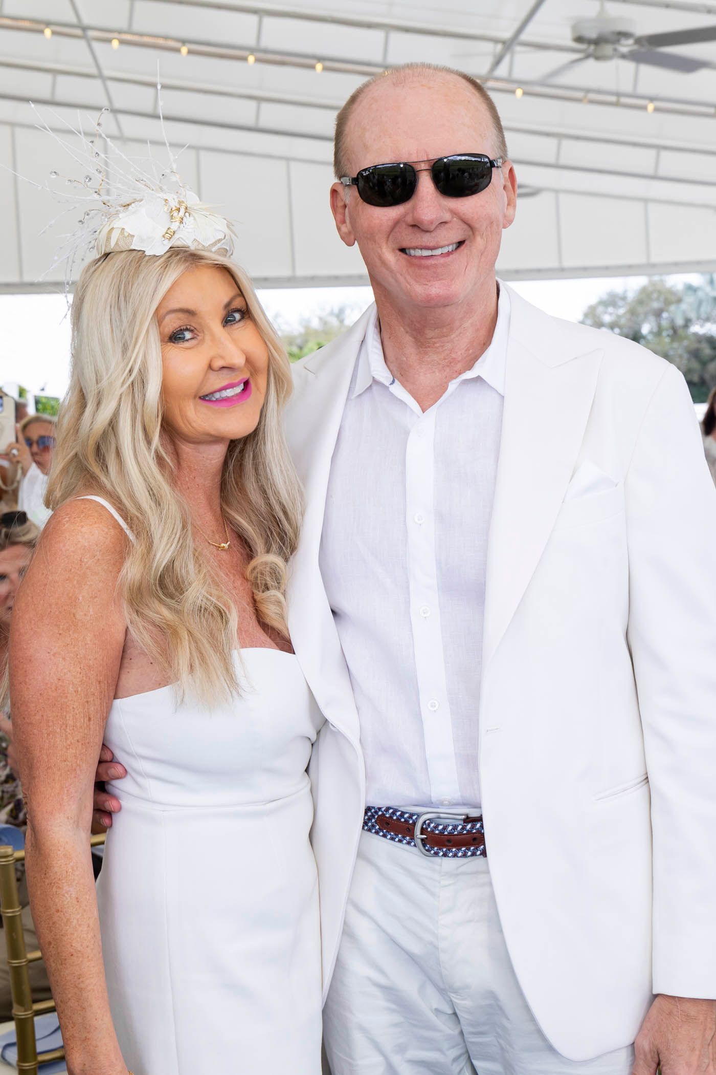 A man and a woman are posing for a picture while wearing all white.