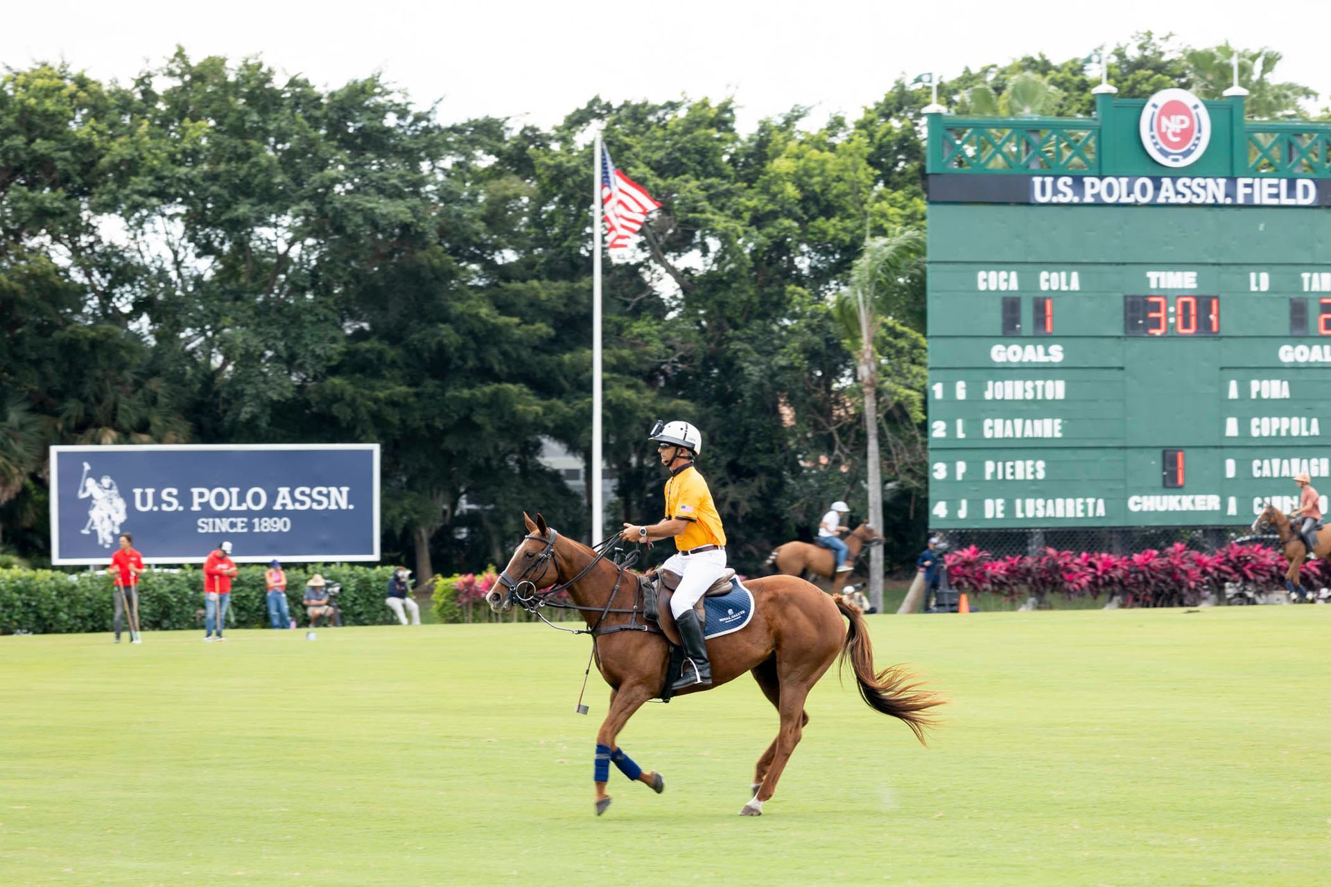 A man riding a horse in front of a scoreboard that says us polo assn field