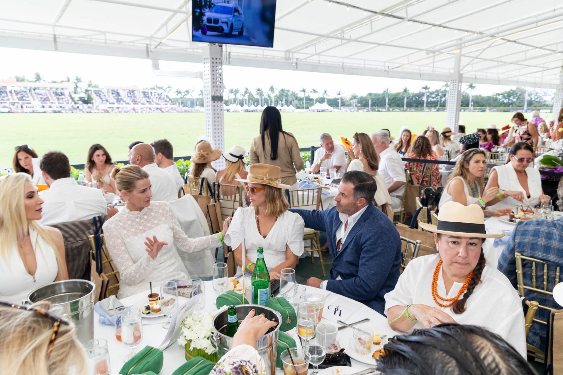 A large group of people are sitting at tables in a tent.
