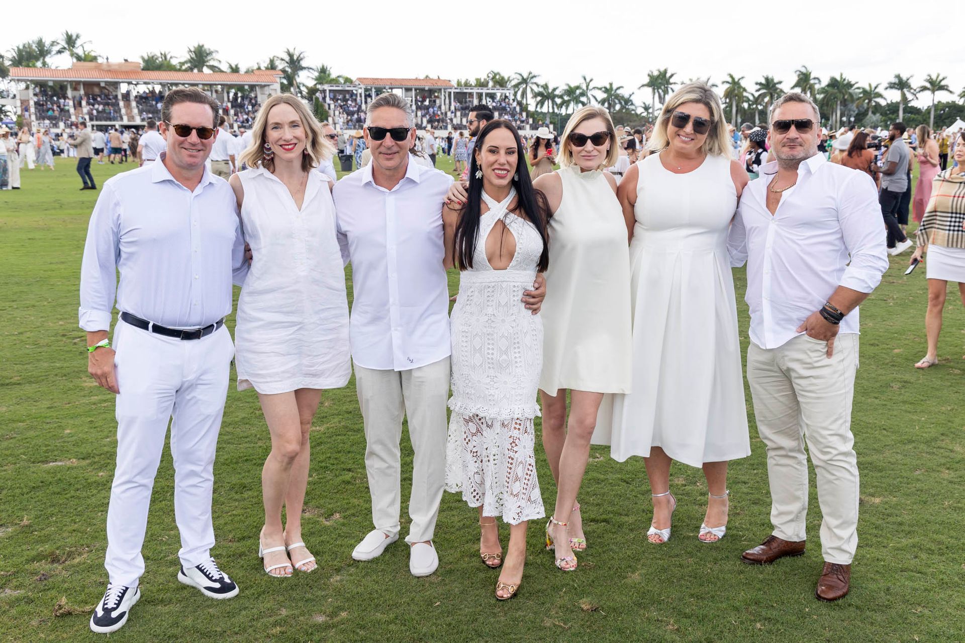A group of people wearing all white are posing for a picture on a field.