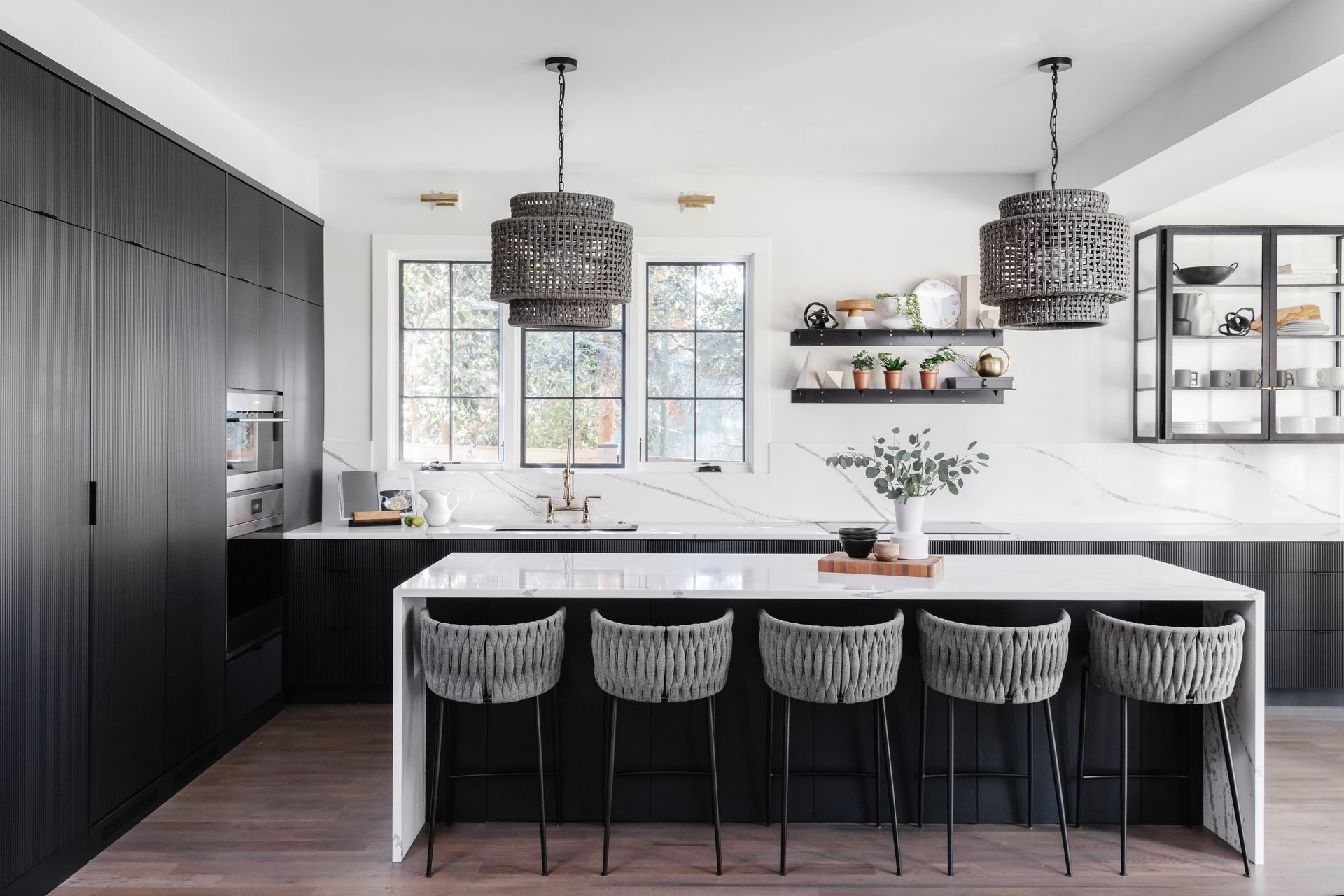 A Kitchen With Black Cabinets And White Counter Tops And Stools