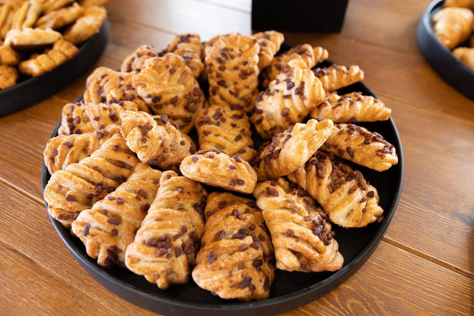 Close-up of a black plate piled with assorted flaky, chocolate-studded pastries.