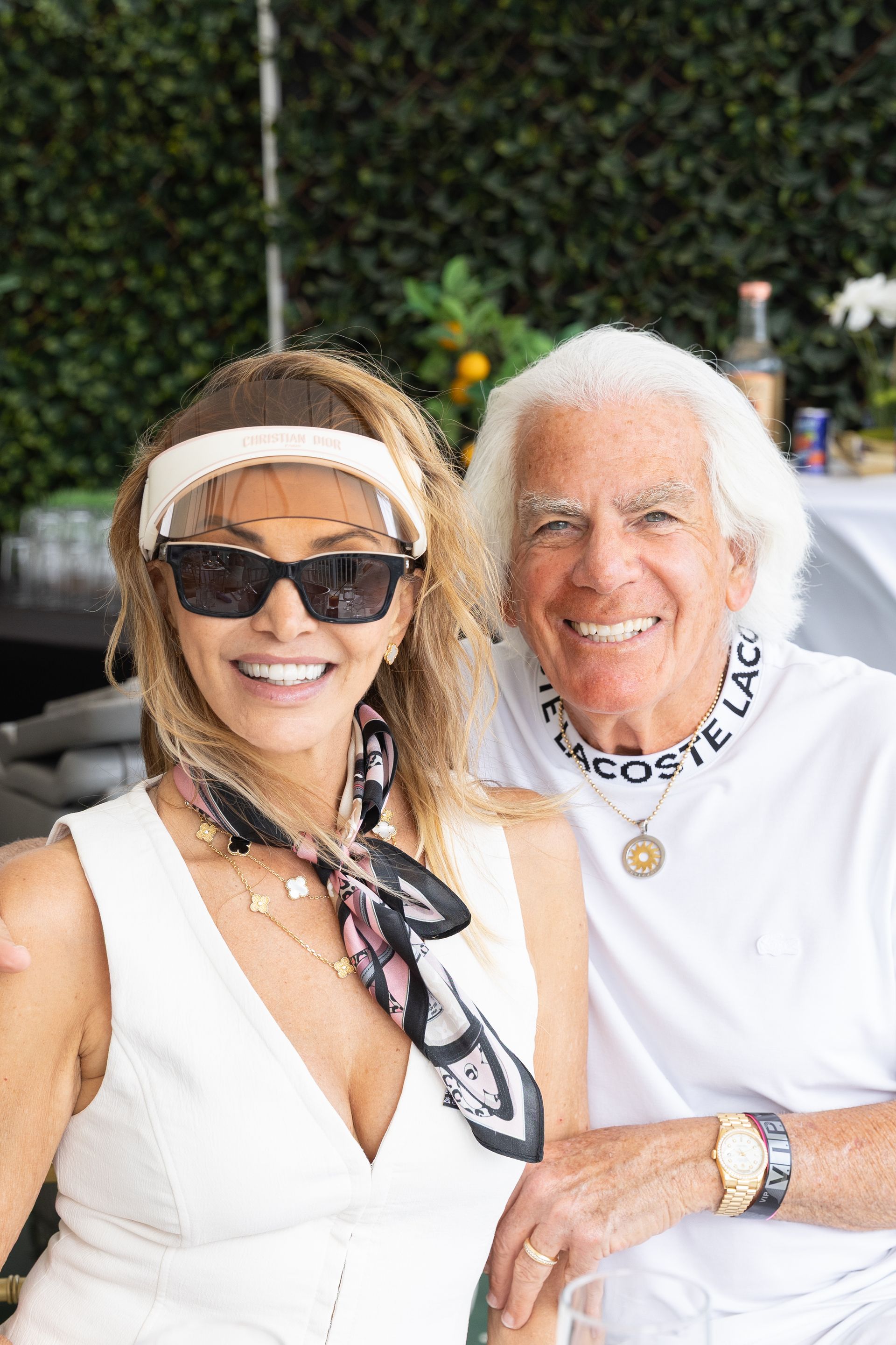 Woman with sunglasses and man smiling, outdoor setting, possibly a party.