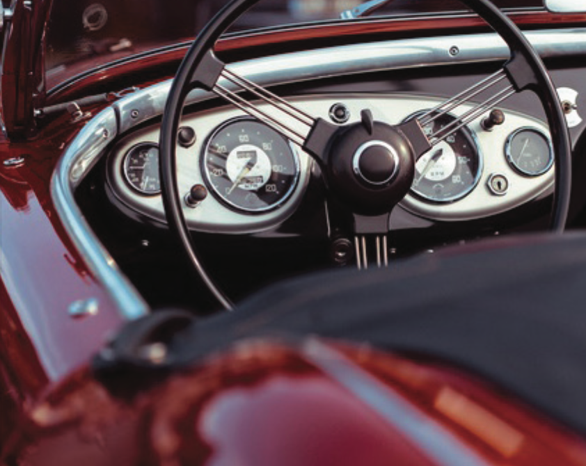 A close up of the steering wheel and dashboard of a red car