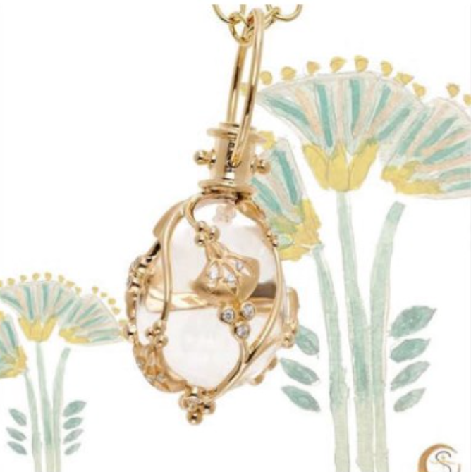 A necklace with flowers in the background is hanging from a gold chain