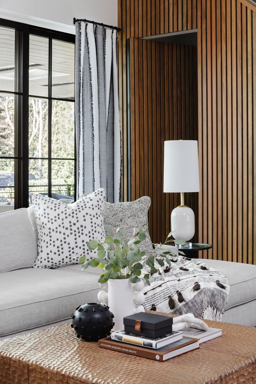 A Living Room With A Couch, Coffee Table, And Lamp