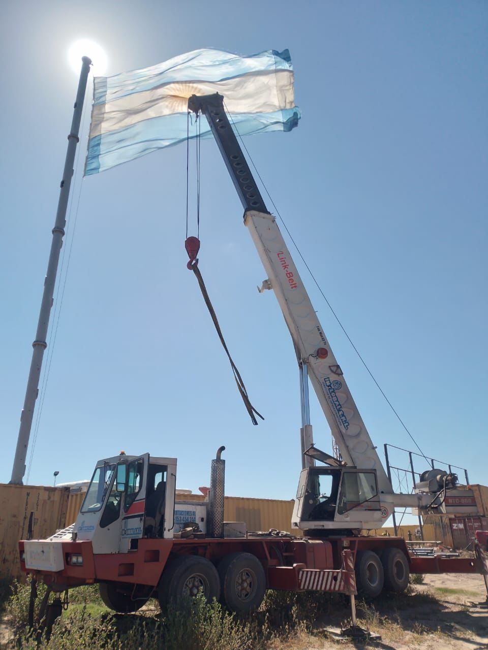 Una gran grúa levanta una bandera en el aire.