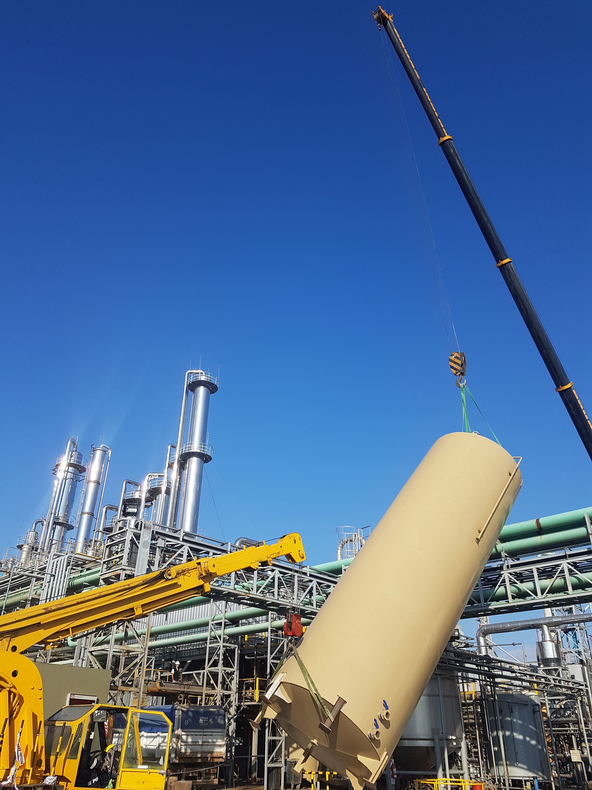 Un gran tanque está siendo levantado por una grúa en una fábrica.