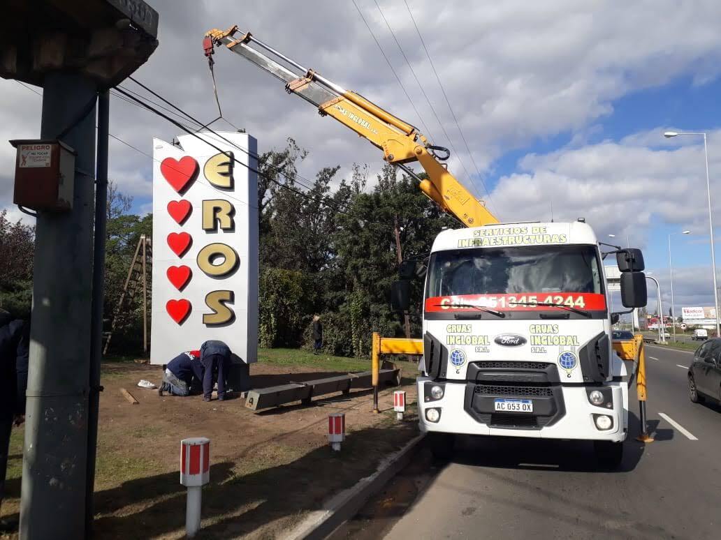 Una grúa levanta un cartel que dice Eros. - Grúas Inglobal SRL
