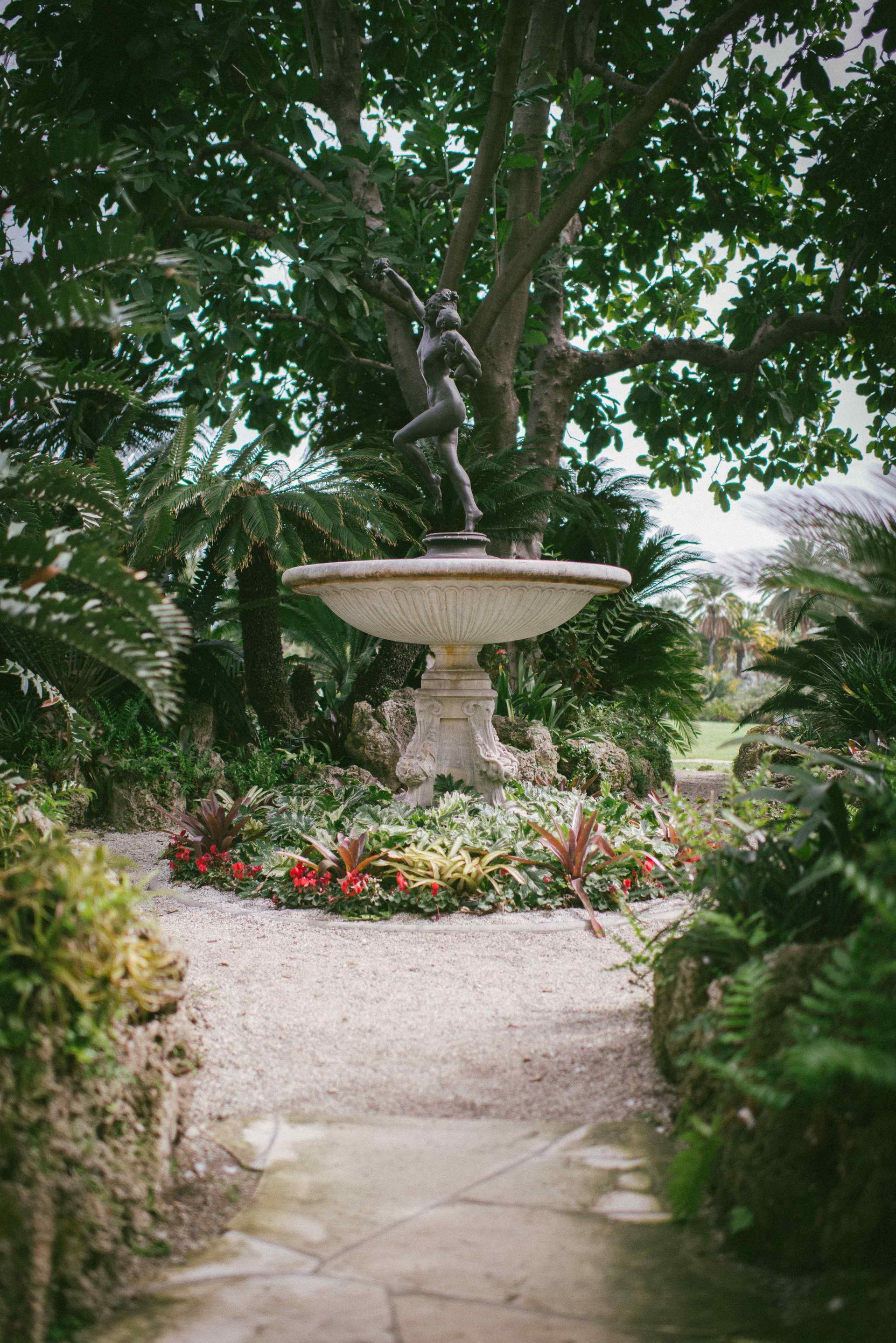 Large Affordable Water Fountain With Statue On Top Surrounded By Sub Tropical Plants