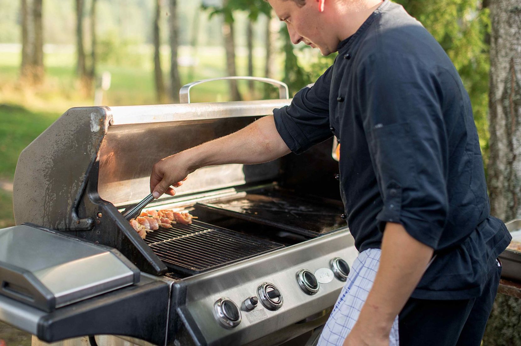 Man Cooking In Backyard Outdoor Kitchen Grill