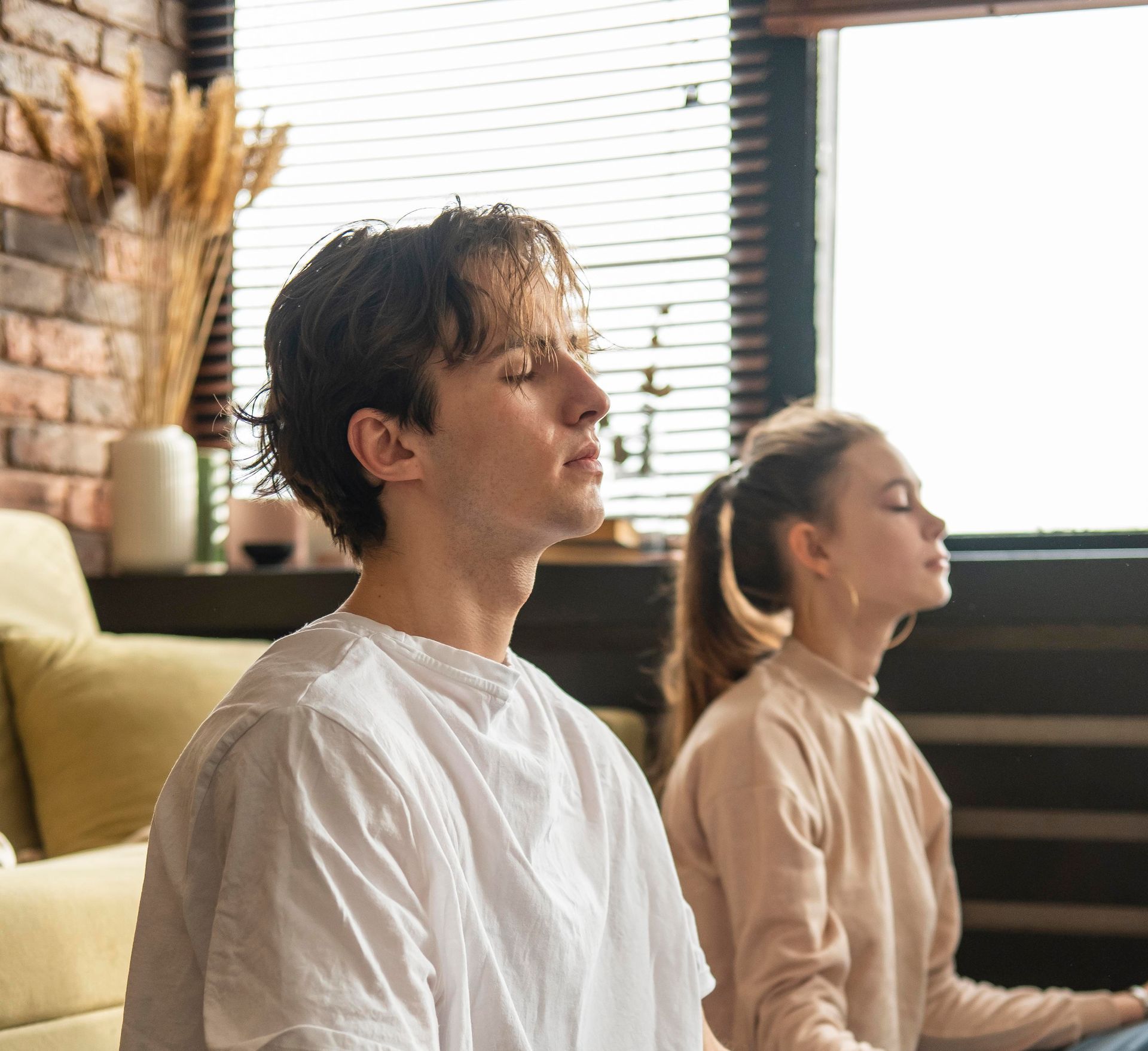Um homem e uma mulher estão sentados em um sofá com os olhos fechados.