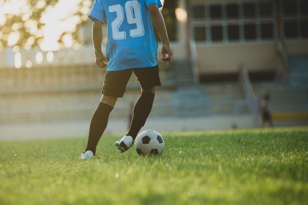 um jogador de futebol está chutando uma bola de futebol em um campo.