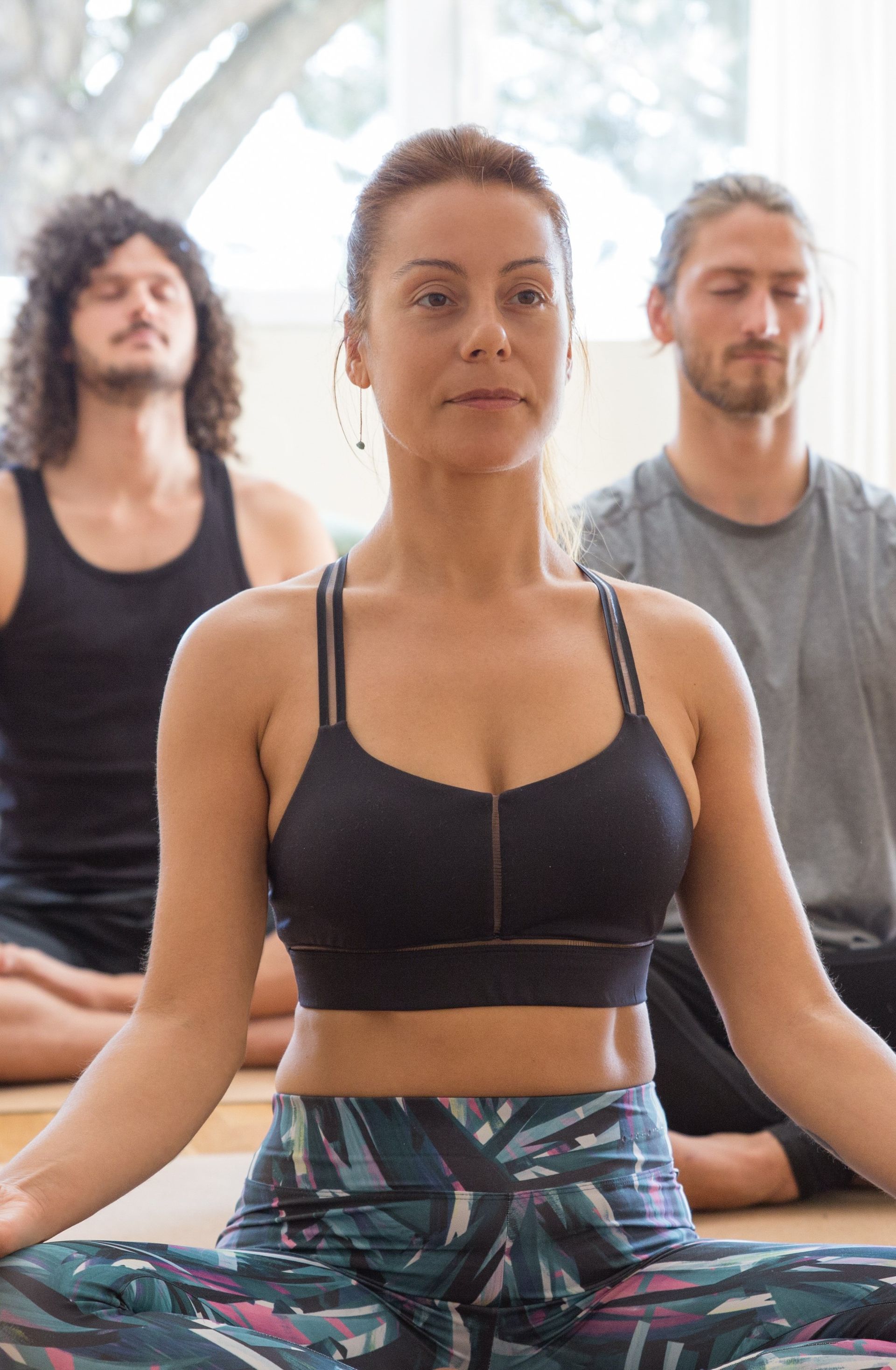 Um grupo de pessoas está sentado em posição de lótus em um tapete de ioga.