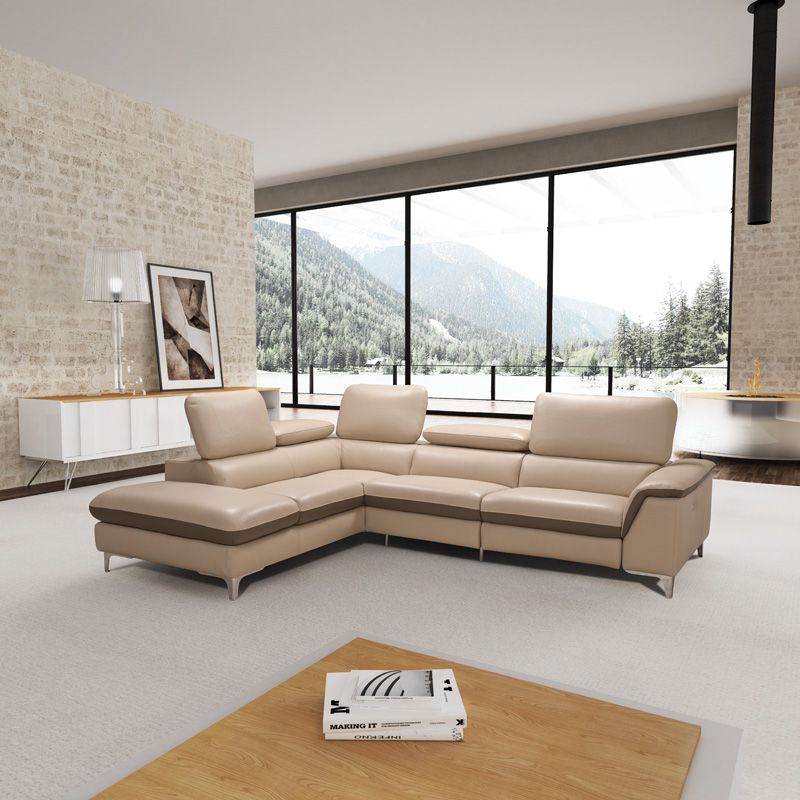 Un moderno divano componibile beige in un luminoso soggiorno con ampie finestre che si affacciano su un paesaggio montuoso.