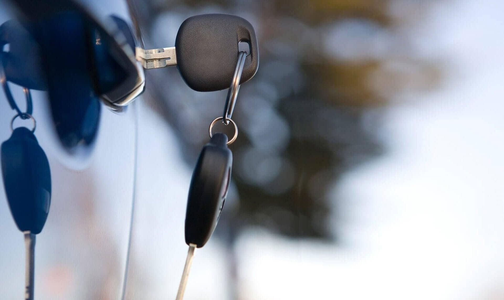 Dos llaves de auto cuelgan de la puerta de un auto.