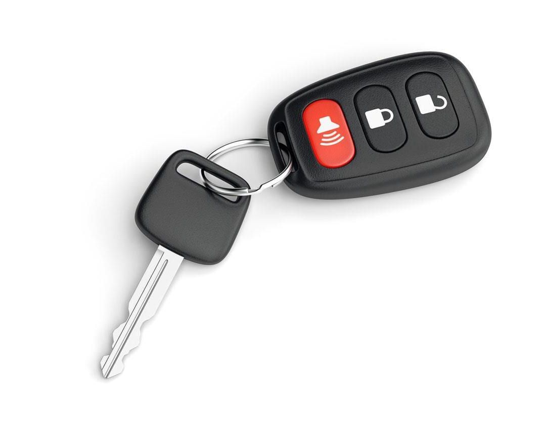 Una llave de coche con un mando a distancia adjunto sobre un fondo blanco.