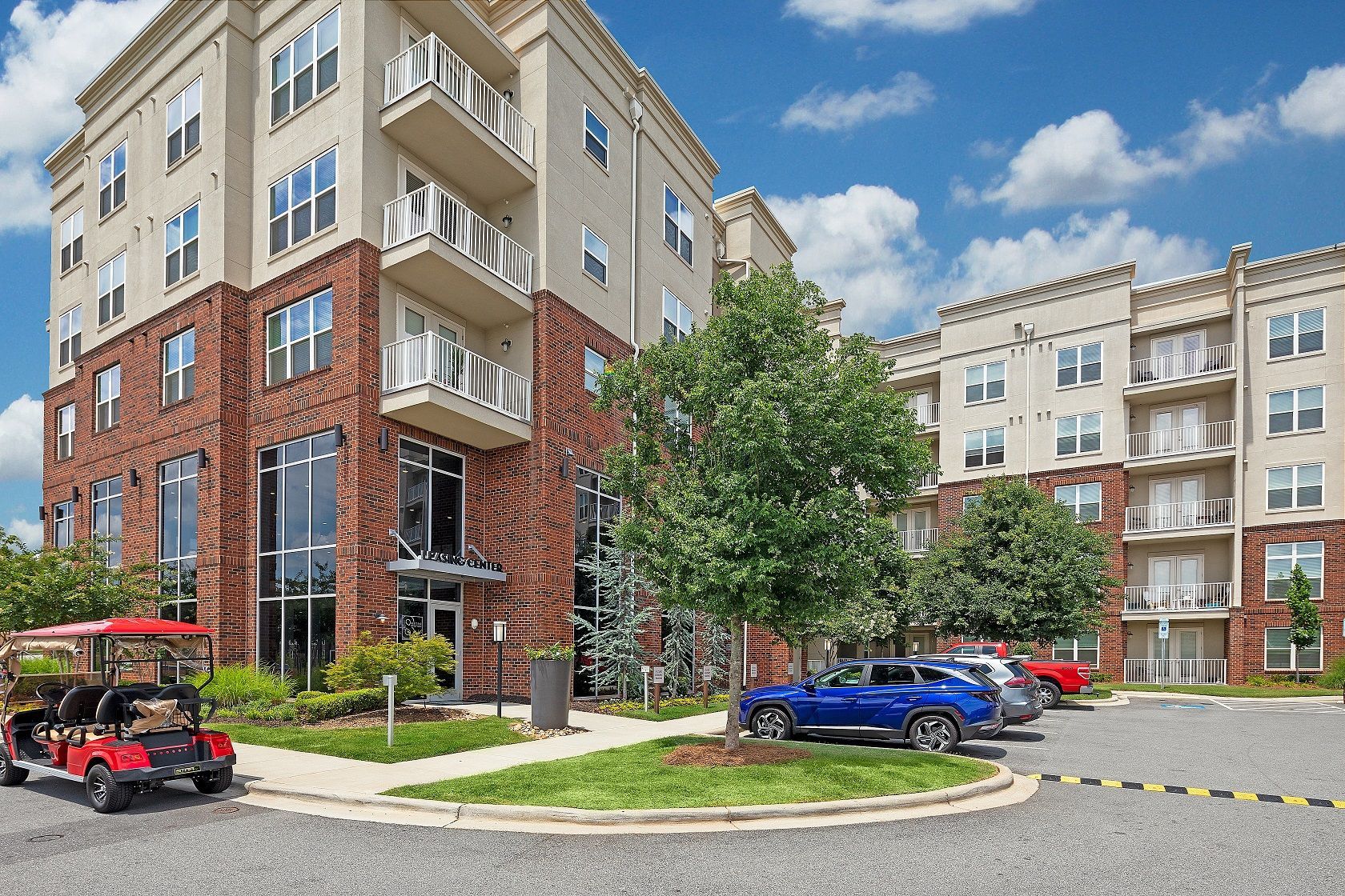 A golf cart is parked in front of a large apartment building.