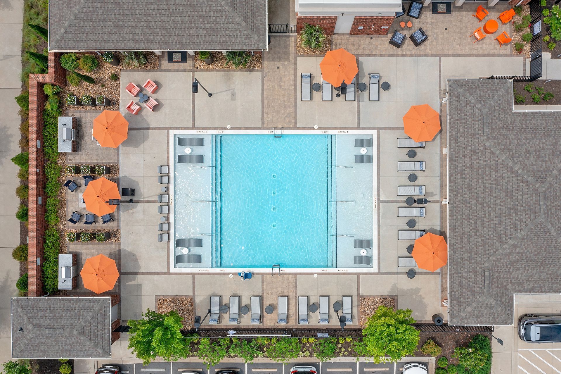 An aerial view of a large swimming pool with orange umbrellas