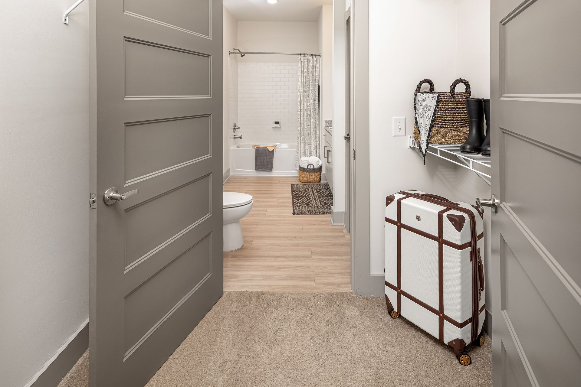 A suitcase is sitting in a hallway next to a bathroom.