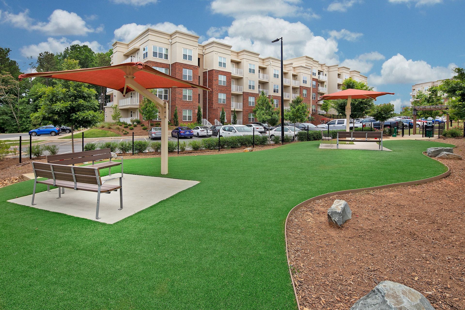 A park with a bench and an umbrella in front of a building.