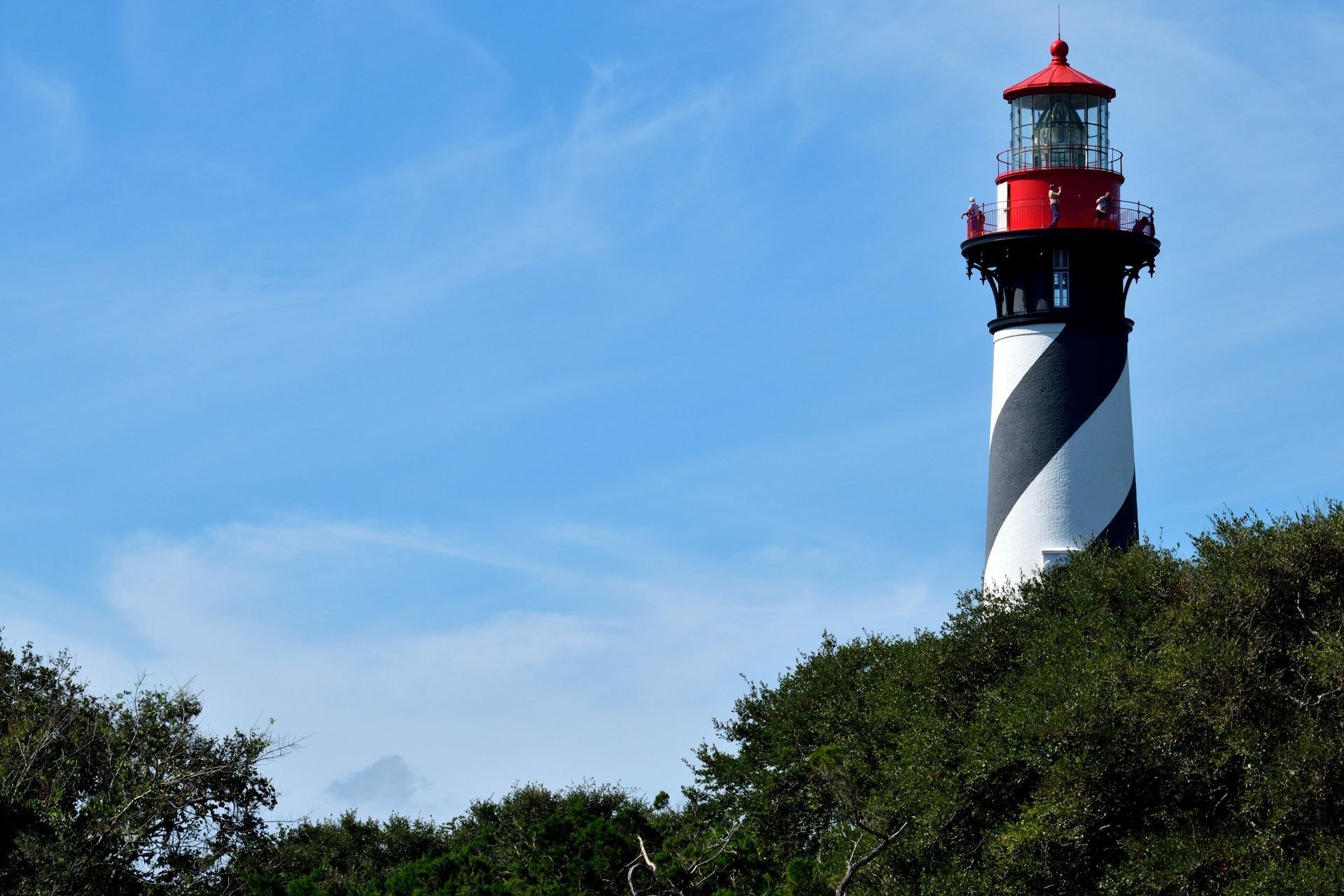 A black and white lighthouse on top of a hill