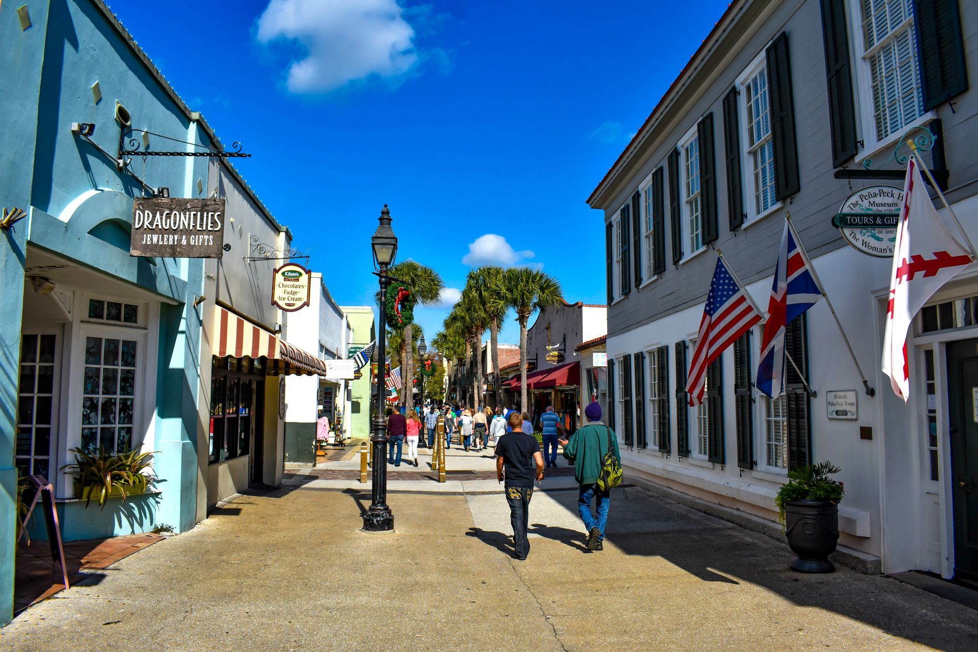 A group of people are walking down a narrow street between two buildings.