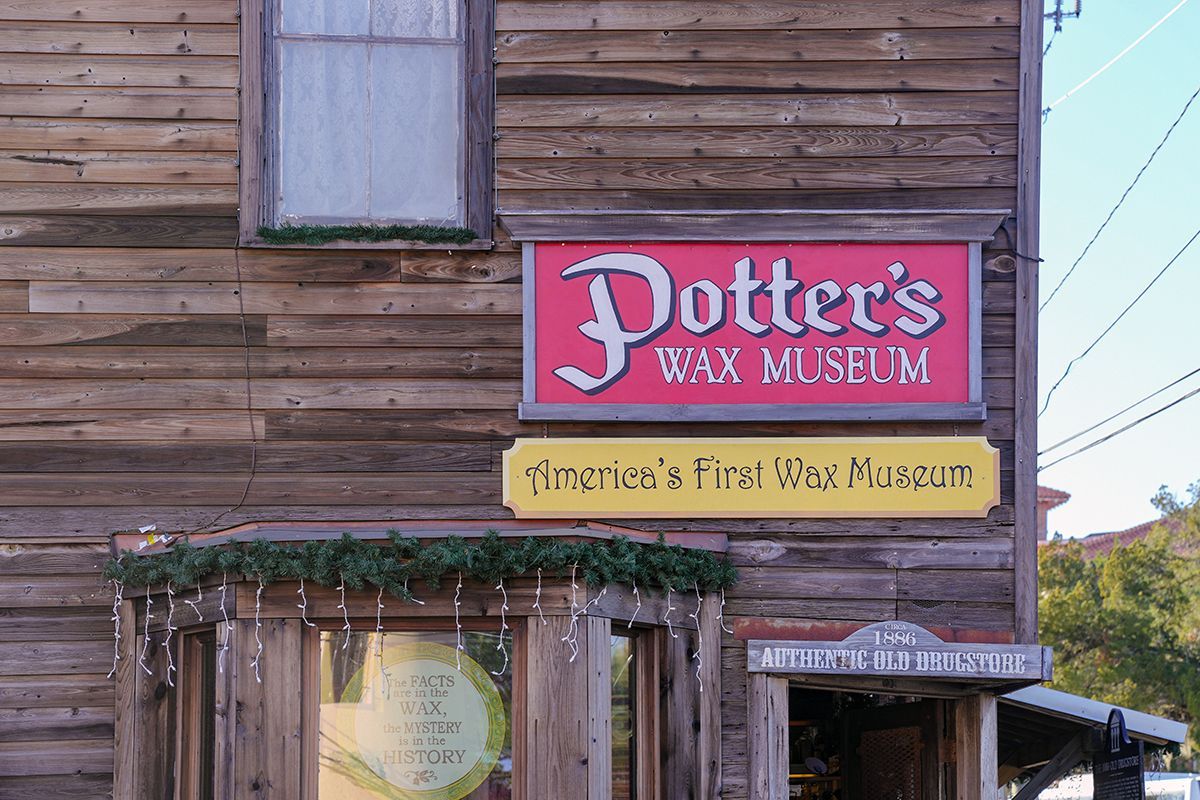 a wooden building with a red sign that says potter 's wax museum